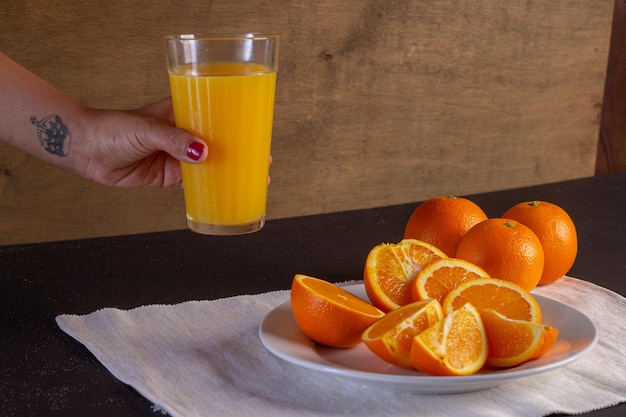 Mano de mujer sostiene un vaso de jugo en una mesa, Fondo de fruta de naranja saludable muchas frutas frutas frescas de naranja, vida sana.