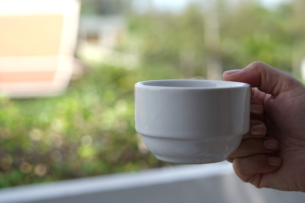 Mano derecha de mujer sosteniendo una taza de café caliente