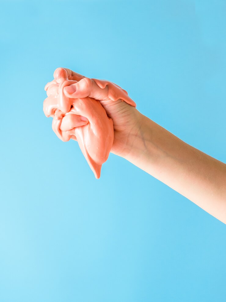 Foto la mano derecha del niño amasa una baba naranja sobre azul.