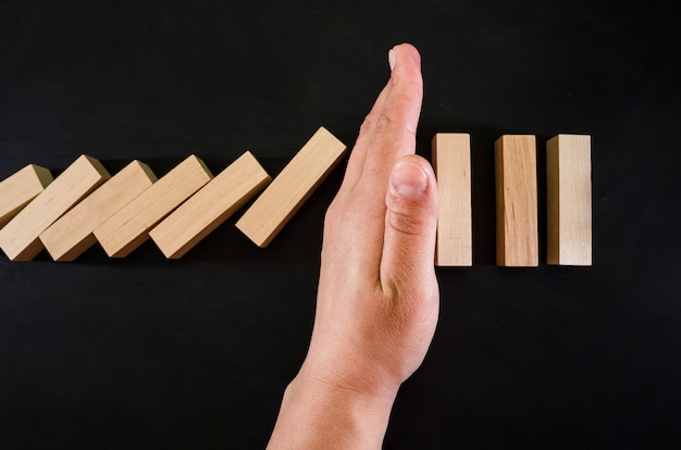 La mano detiene la caída de bloques de madera en negro.