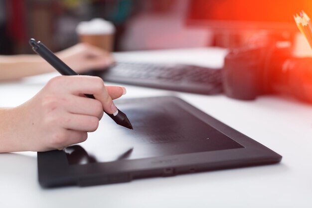 Mano del diseñador con un bolígrafo en una tableta