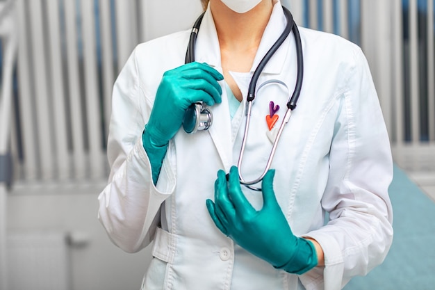 Mano del doctor en bata blanca sosteniendo un fonendoscopio en el fondo de una sala de hospital. Medicina, salvavidas, médicos generales.