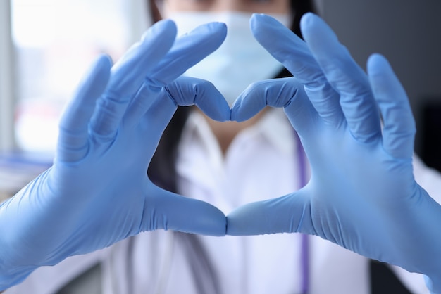 La mano del doctor en guantes médicos protectores cubre el primer del corazón. Concepto de atención cardiológica