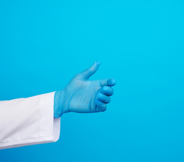 Foto la mano del doctor lleva un guante de goma estéril azul que sostiene un objeto