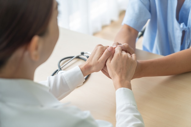 Mano de doctora sosteniendo a su paciente senior