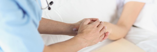 La mano de la doctora toma de la mano del paciente acostado en el hospital, disminución y apoyo de malas noticias