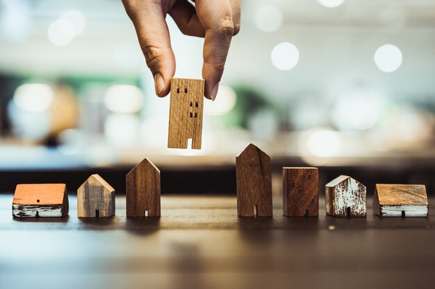 Mano eligiendo el modelo de mini casa de madera del modo en la mesa de madera