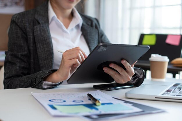 Mano de empresaria trabajando con una nueva computadora moderna usando un teléfono inteligente y una tableta como concepto en la oficina