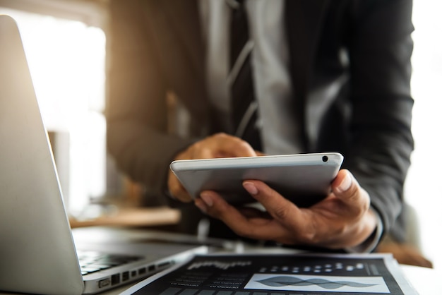 Mano de la empresaria trabajando con la nueva computadora moderna usando el teléfono inteligente y la tableta como concepto