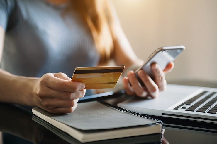 Foto mano de la empresaria usando teléfonos inteligentes, pagos de tableta y sosteniendo tarjetas de crédito compras en línea, canal omnidireccional, computadora con teclado de acoplamiento de tableta digital en la oficina a la luz del sol