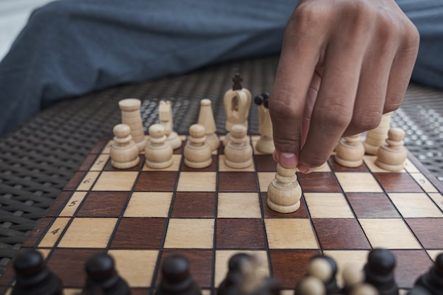 Mano del empresario moviendo la figura de ajedrez en el juego de éxito de la competencia