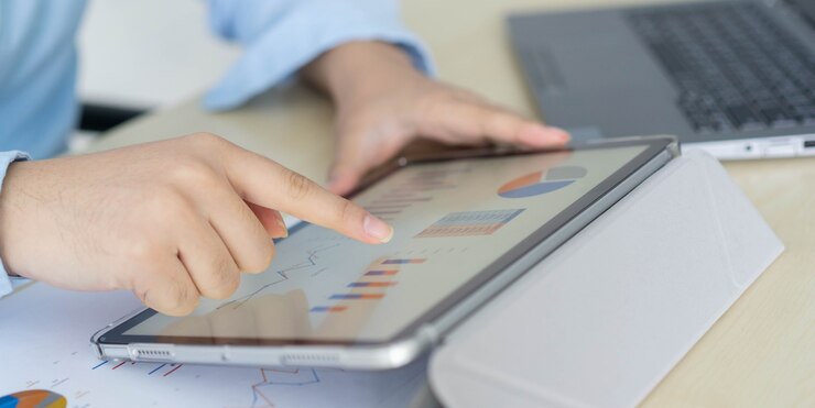 Foto la mano del empresario usa una tableta digital y un informe financiero abierto para verificar las estadísticas comerciales