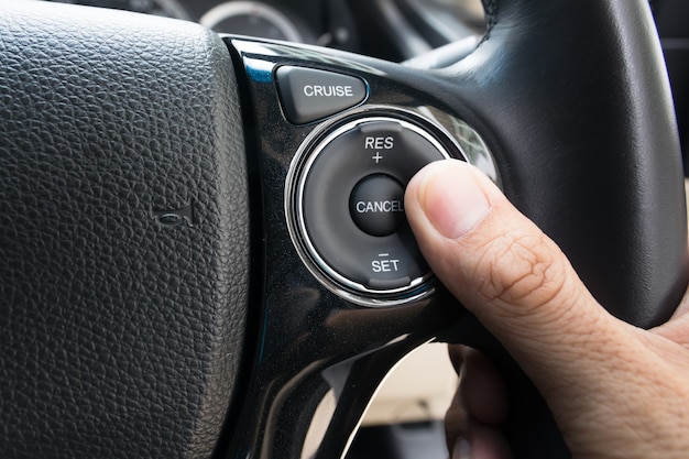 la mano empuja los botones de control de crucero en el automóvil moderno y la limitación de velocidad