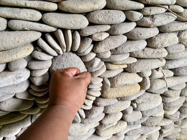 Una mano empuja un círculo de rocas en una pared.