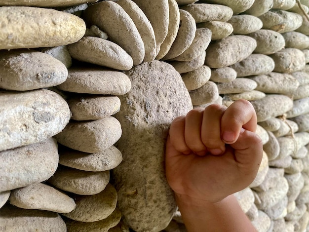 Una mano empuja una piedra que está apilada una encima de la otra.