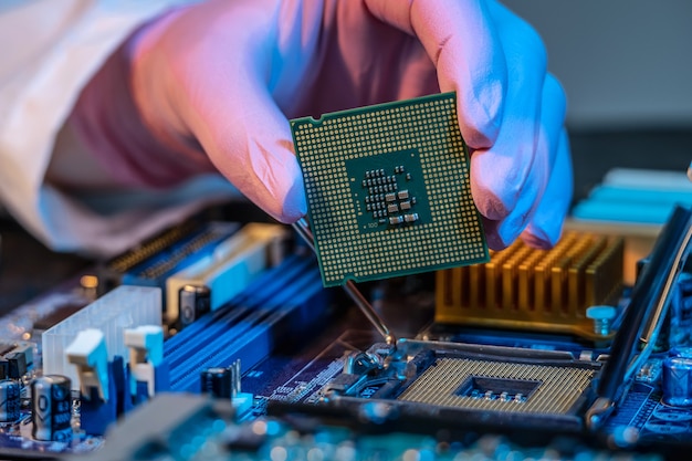 La mano enguantada de los ingenieros sostiene el chip de la CPU contra el fondo de la placa base