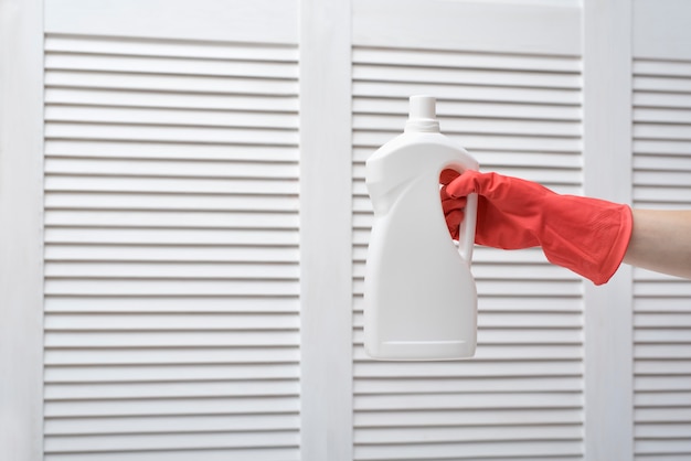 Foto mano enguantada sosteniendo una gran botella blanca.