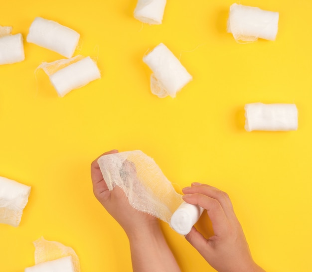 Mano envuelta con una venda de gasa blanca sobre amarillo