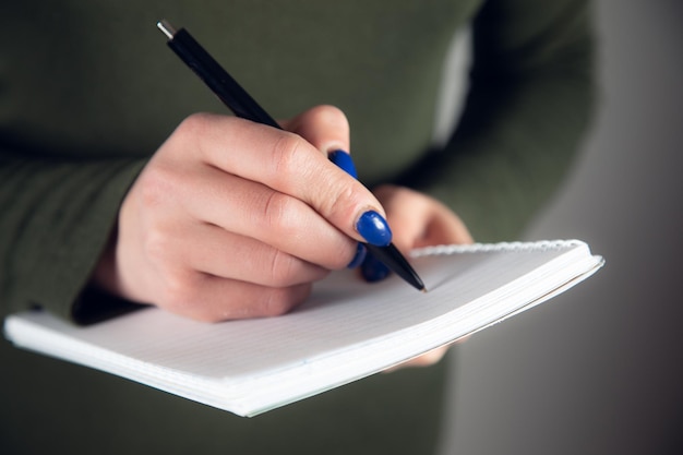 Mano escribe con un bolígrafo en un cuaderno