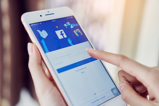 La mano está presionando la pantalla de Facebook en smartphone