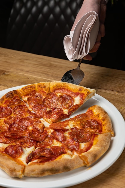 Una mano está recogiendo una porción de pizza de un restaurante.