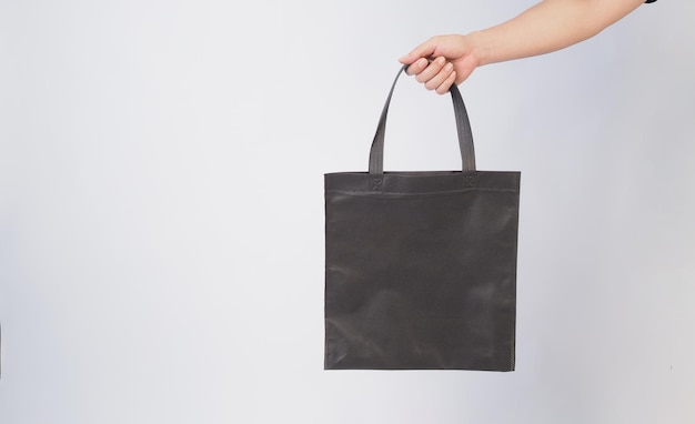 La mano está sosteniendo una bolsa de Spunbond negra sobre un fondo blanco x9