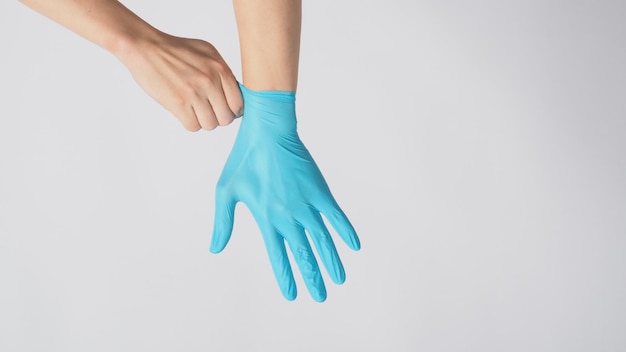 La mano está tirando y la mano derecha usa guantes de látex azul sobre fondo blanco