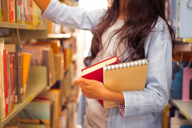 mano del estudiante sostenga el libro para leer en la biblioteca de la universidad