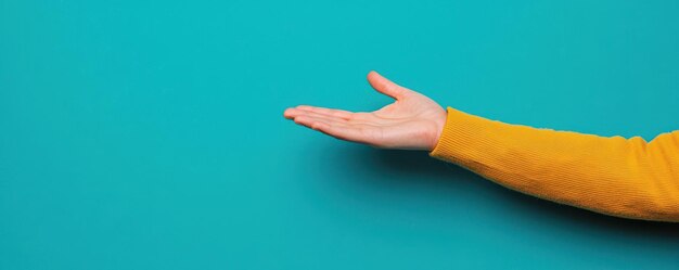 la mano extendida contra un fondo turquesa vibrante que simboliza la apertura y la invitación esto transmite una sensación de calidez y accesibilidad