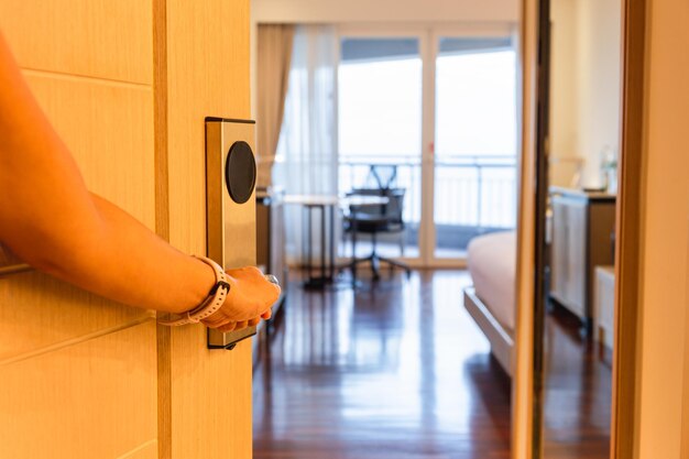 Foto mano femenina abriendo la puerta de madera de la habitación del hotel