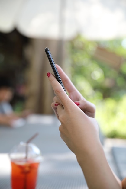 Mano femenina con acciones de comercio de teléfonos inteligentes en línea en una cafetería al aire libre, concepto de negocio