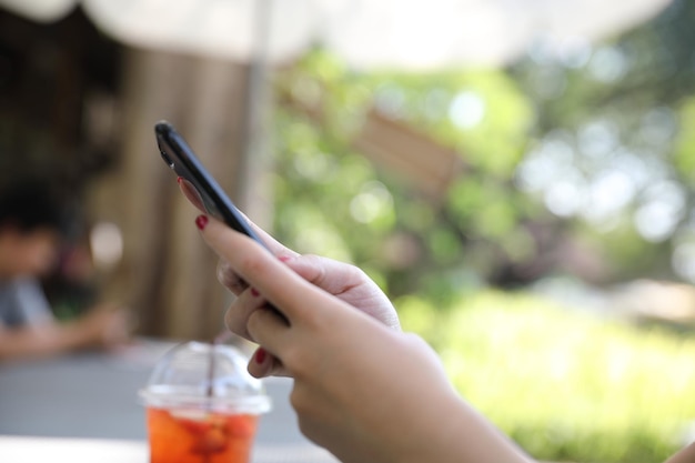 Mano femenina con acciones de comercio de teléfonos inteligentes en línea en una cafetería al aire libre, concepto de negocio