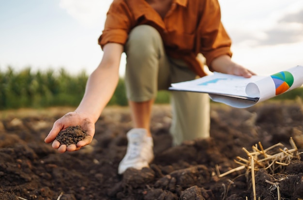 La mano femenina de un agricultor experto recoge el suelo y comprueba la salud del suelo antes de cultivar una semilla de verdura