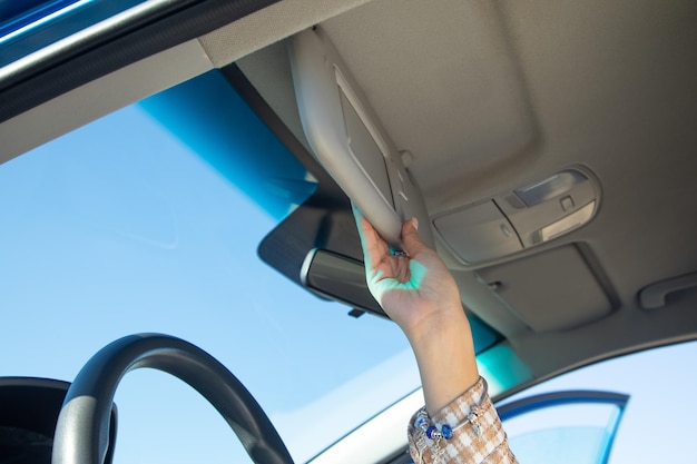 Mano femenina ajustando el parasol en un coche