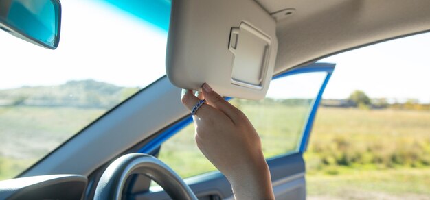 Mano femenina ajustando el parasol en un coche