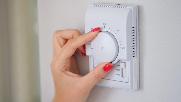 Mano femenina ajustando la temperatura del acondicionador de aire con cierre de rodillos