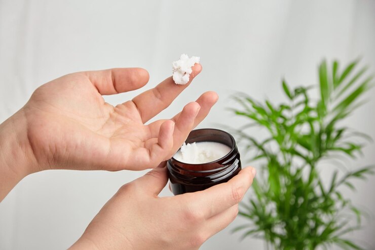 Mano femenina aplicando manteca de karité pura Tratamiento antienvejecimiento Producto para el cuidado del cabello de la piel cosmética natural