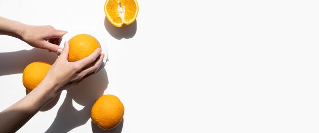 La mano femenina aprieta el jugo de las naranjas en un tazón de mano sobre un fondo blanco Vista superior plana Lay Banner