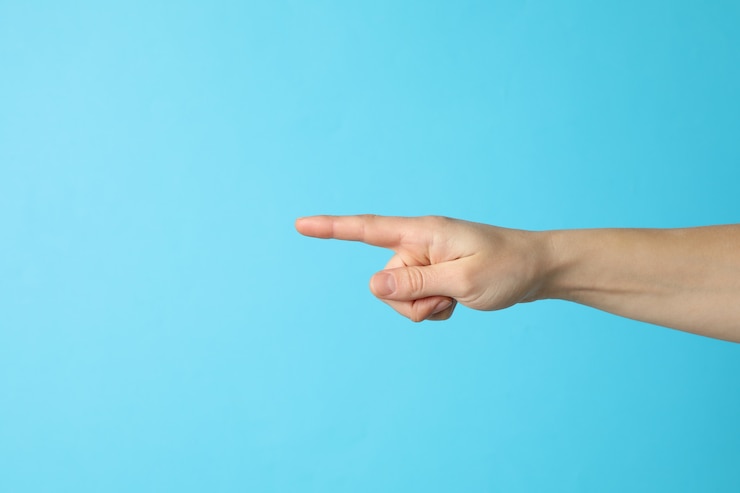 Foto mano femenina apuntando sobre fondo azul, espacio para texto