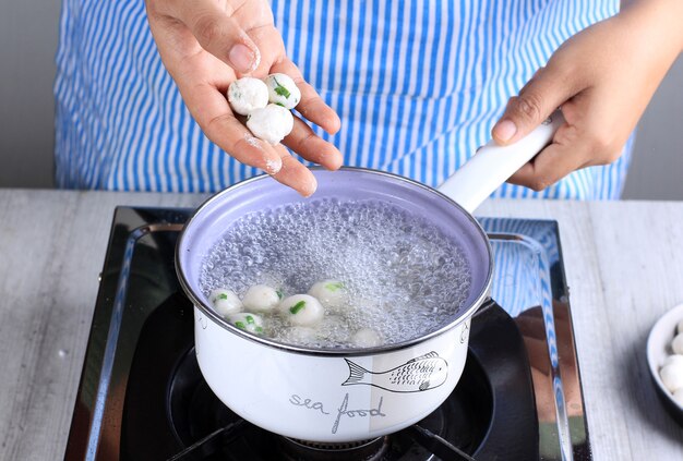 Mano femenina asiática Chef Cilok casero hervido, bocadillo popular de comida callejera hecho con harina de tapioca