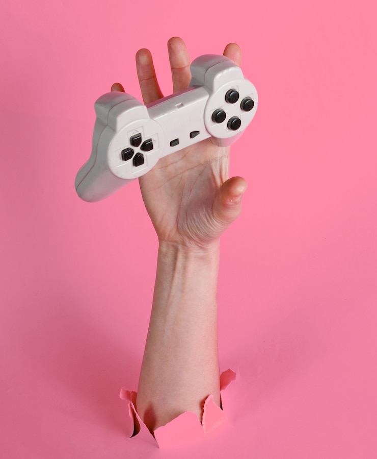 Foto la mano femenina atrapa el mando a través del papel rosa rasgado. concepto creativo minimalista