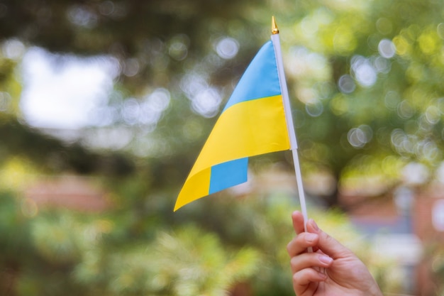 Mano femenina con una bandera azul y amarilla Día de la Independencia de Ucrania