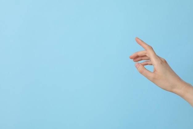 Mano femenina bien cuidada en un fondo azul claro lugar para el texto