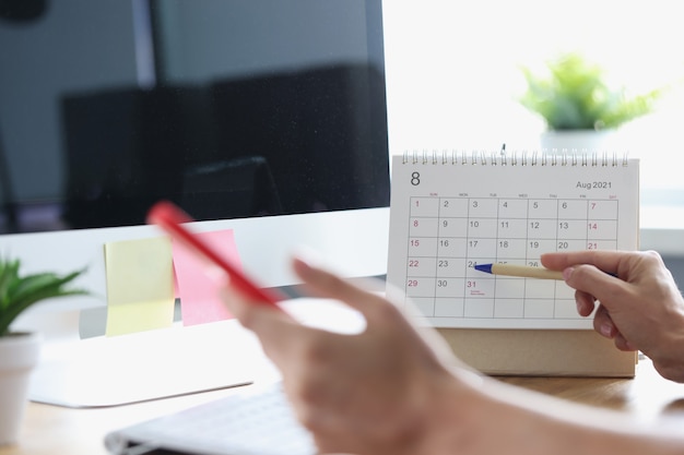 En mano femenina, un bolígrafo de teléfono inteligente con calendario en el concepto de planificación de procesos de negocio en el lugar de trabajo