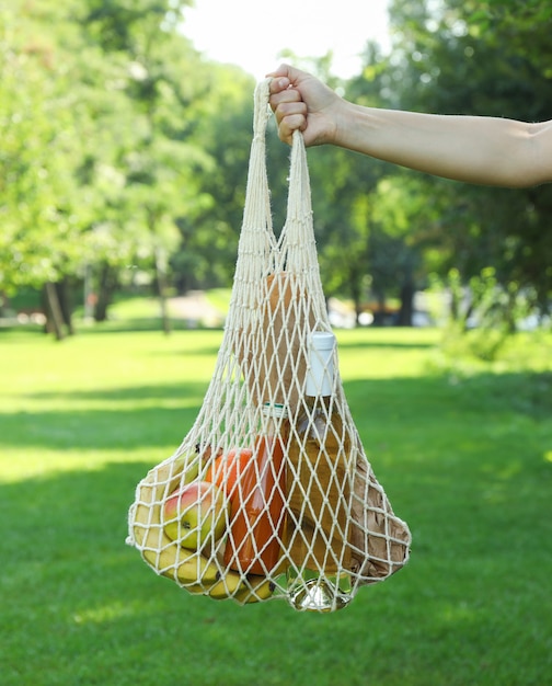 Mano femenina con bolsa de cadena en el parque