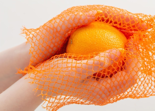 Mano femenina con bolsa de cuerda naranja y sintética.