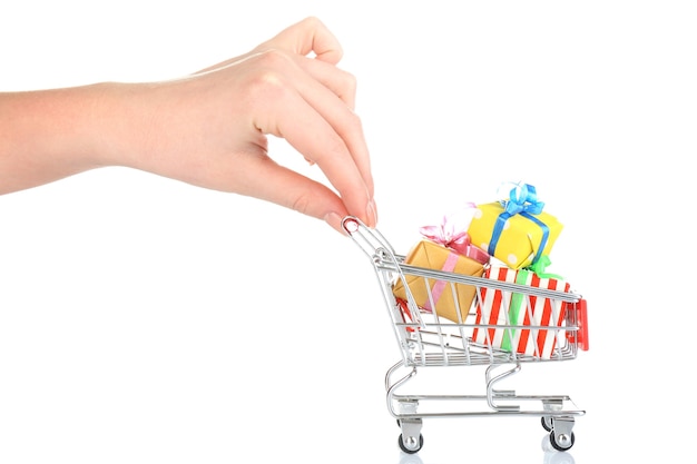 Mano femenina con carrito de compras pequeño lleno de regalos, aislado en blanco