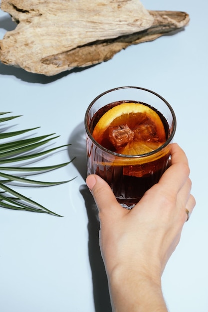 Mano femenina con cóctel de mezcal negroni