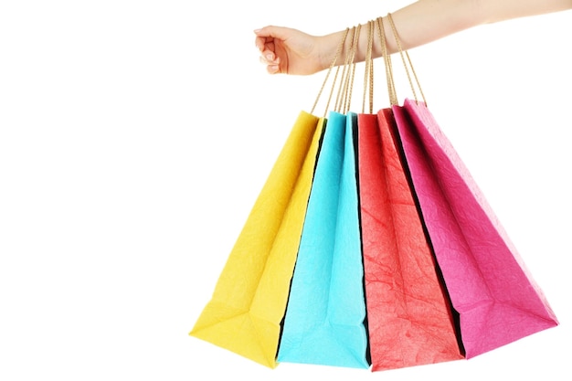 Mano femenina con coloridas bolsas de papel de compras aisladas en blanco