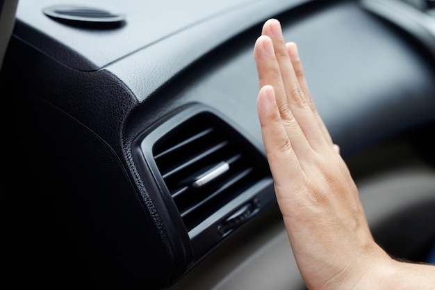 Mano femenina comprobando el enfriamiento del aire acondicionado en el coche